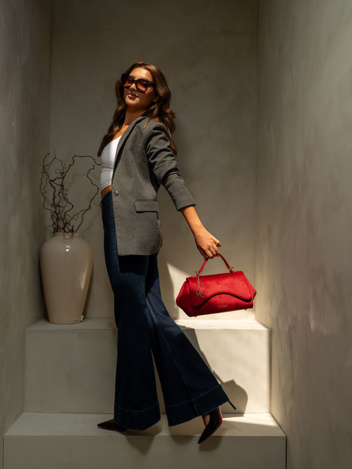A woman carrying The Becoming in Rouge through a warm studio